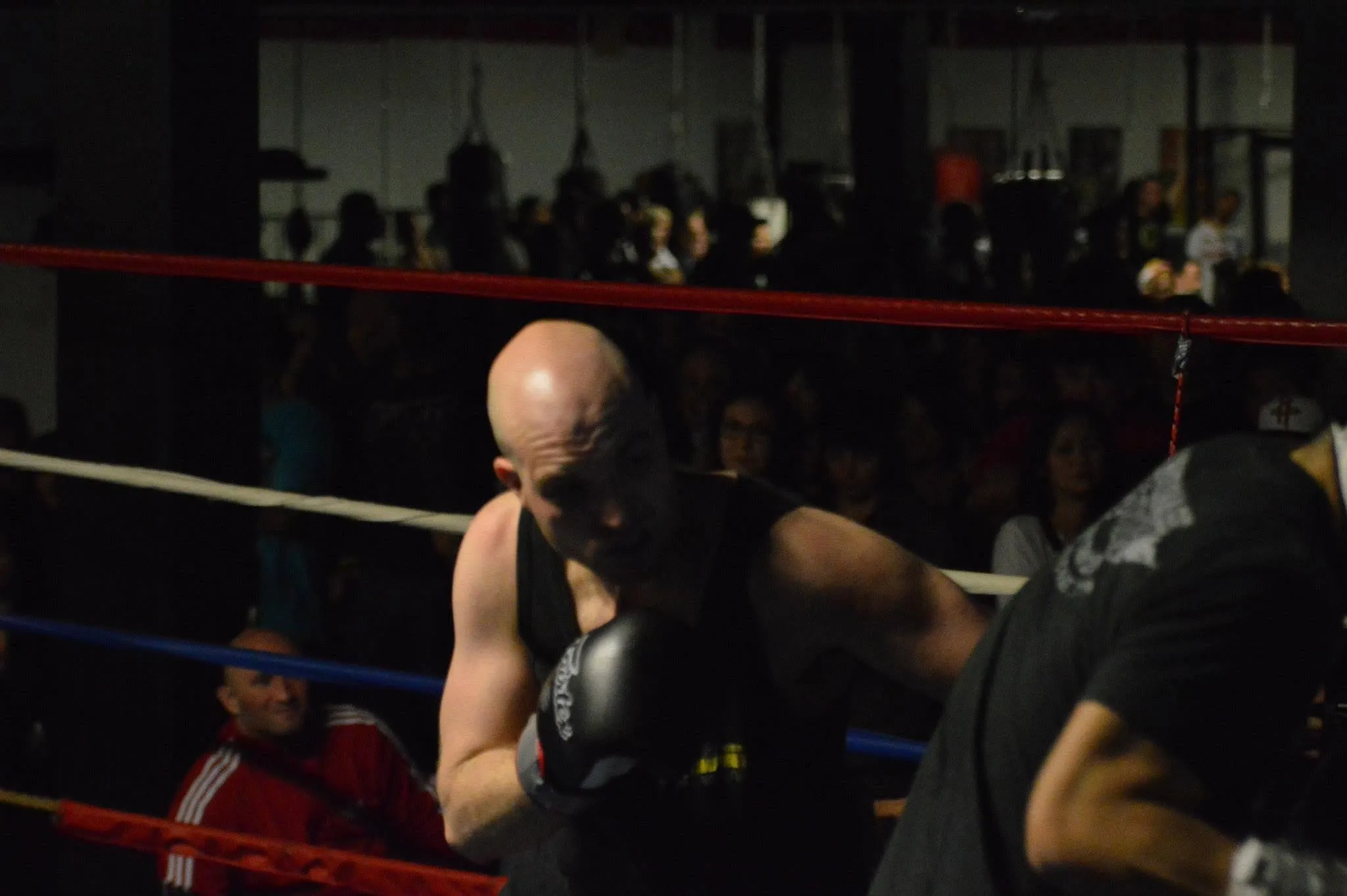 Eitan in close during a fight, crowd watching from the dark